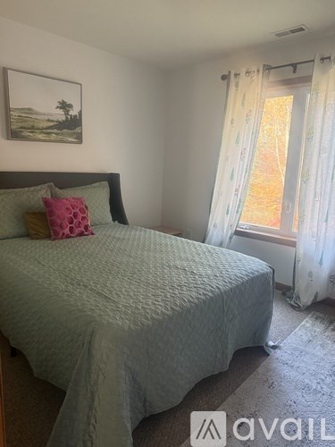 A bedroom with a bed, pillow, and a painting on the wall.