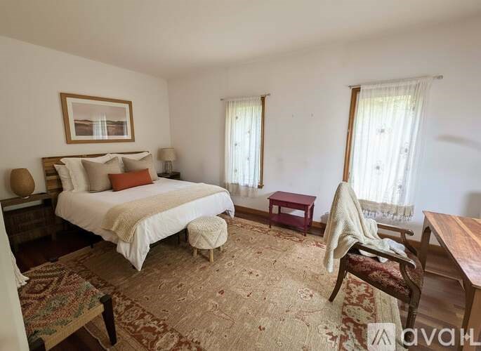 A bedroom with a large bed, a chair, and a rug.