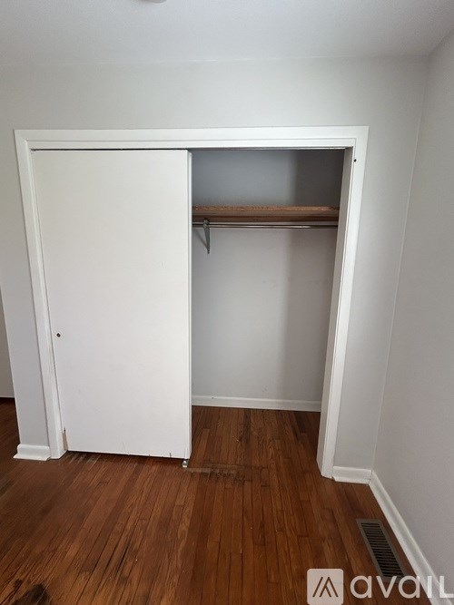 A white closet with a shelf and a wooden floor.