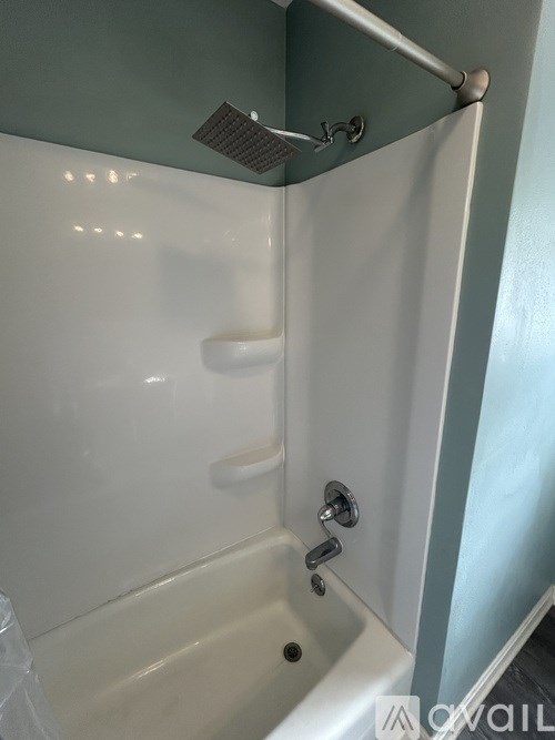 A white bathtub with a silver faucet and a silver shower head.