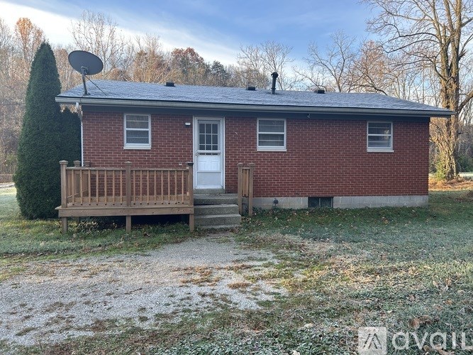 A small red brick house with a white door and a satellite dish on the roof.