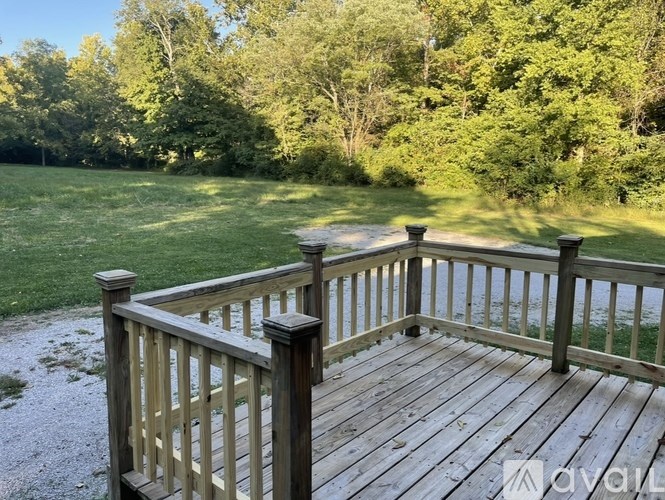 A wooden deck overlooks a grassy area with trees in the background.