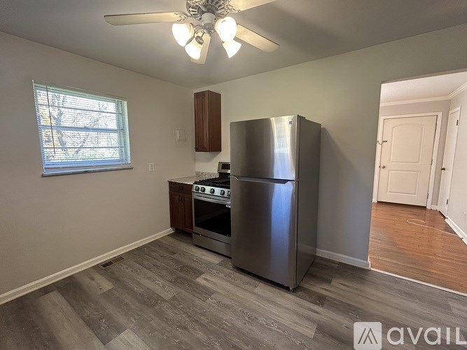 A kitchen with a stainless steel refrigerator and oven, wooden cabinets, and a ceiling fan.