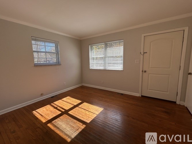 A room with wooden floors and a window with blinds.