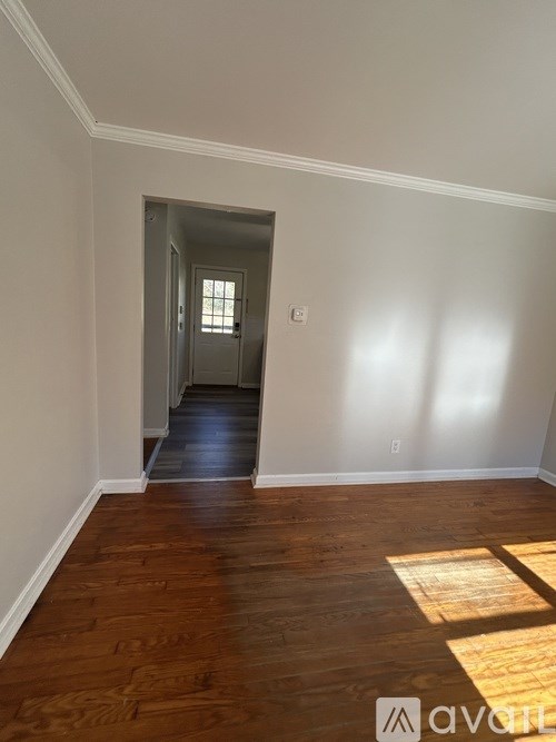 A hallway with wood floors and a door at the end.