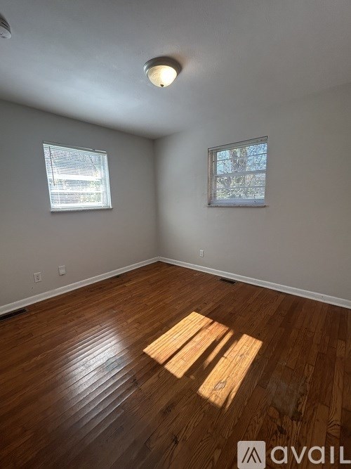 A room with wooden floors and two windows.