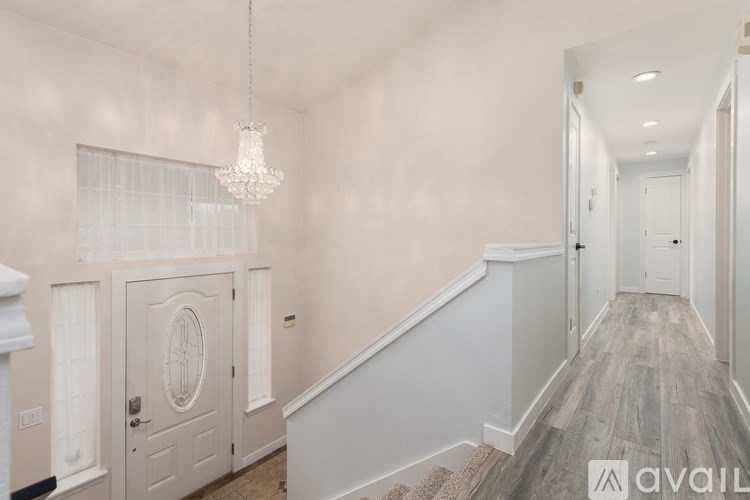 A hallway with a chandelier and a staircase.