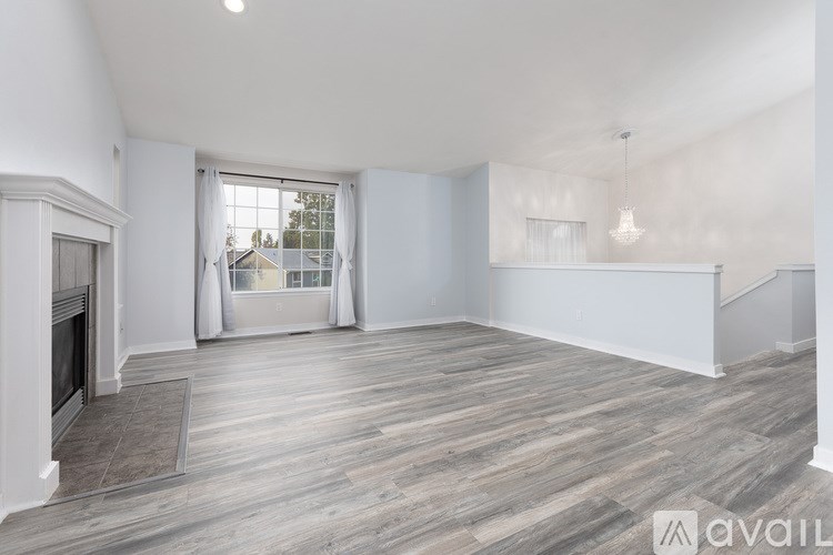 A spacious living room with a fireplace and a large window.