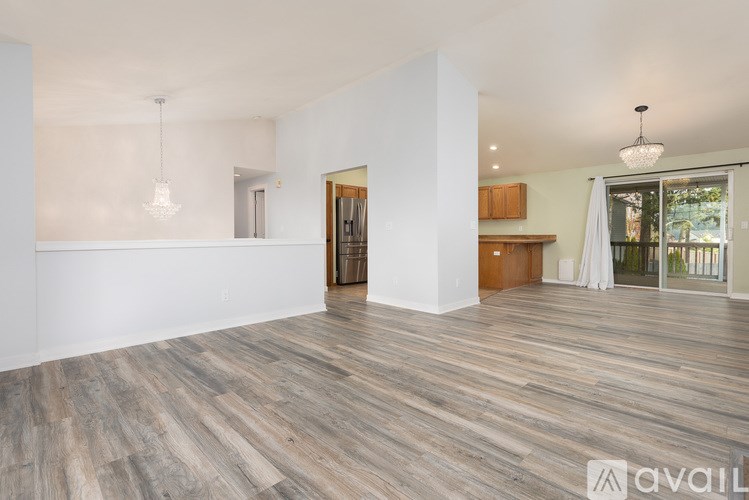 A spacious room with wooden flooring and a large window.