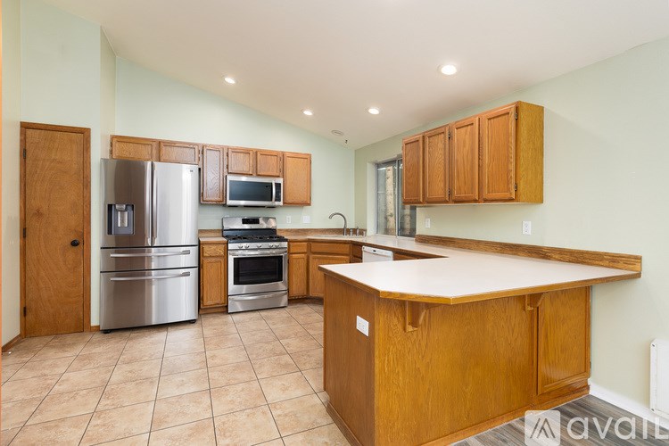 A kitchen with wooden cabinets and a stainless steel refrigerator.