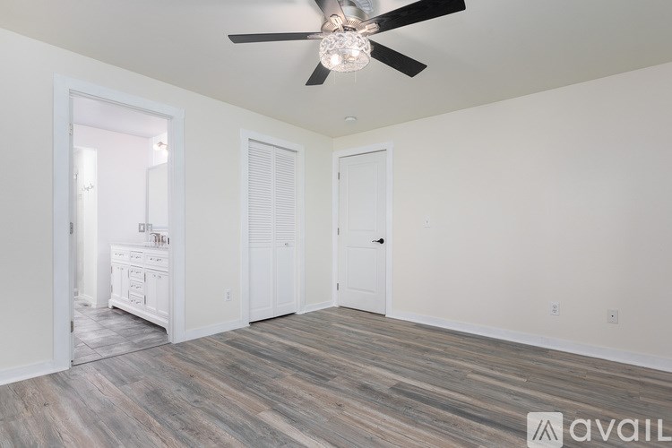 A room with a ceiling fan and wooden flooring.