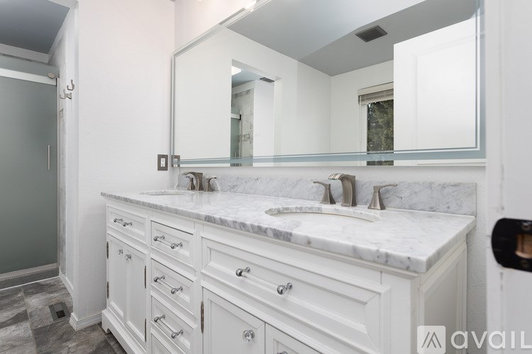 A bathroom with a marble countertop and white cabinets.