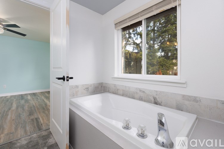 A bathroom with a large tub and a window.