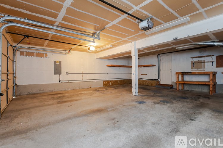 A large, empty room with a concrete floor and a white ceiling with exposed pipes.