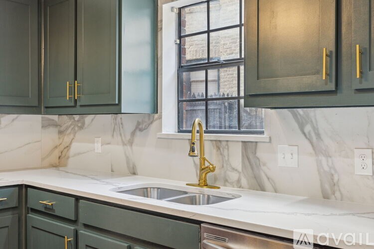 A kitchen with green cabinets and a marble countertop.