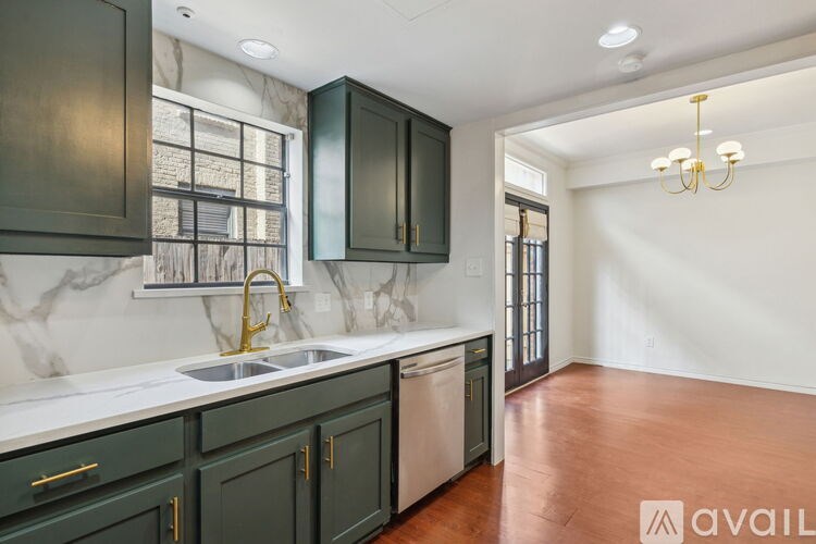 A kitchen with dark green cabinets and a marble backsplash.