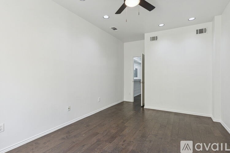 A spacious room with a ceiling fan and wooden flooring.