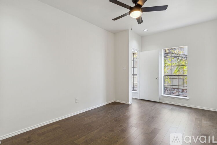 A spacious room with a ceiling fan and wooden flooring.