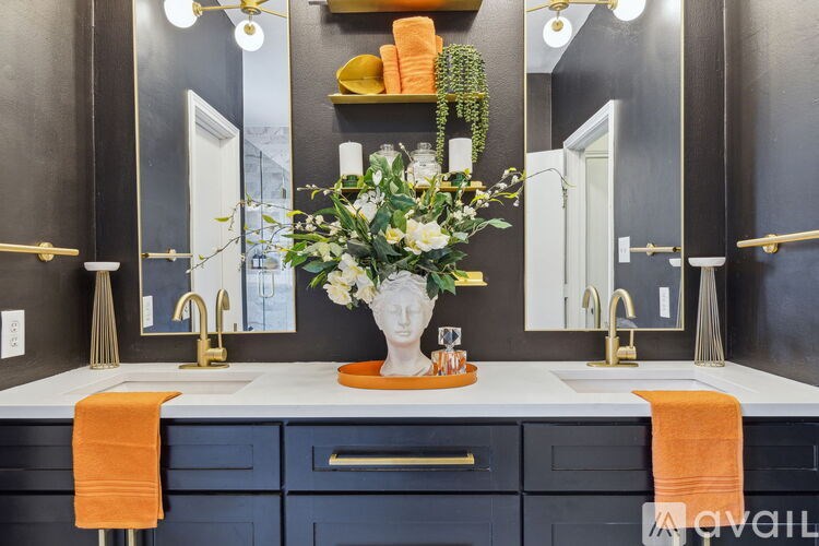 A bathroom with two sinks, a large mirror, and a vase of flowers on the counter.