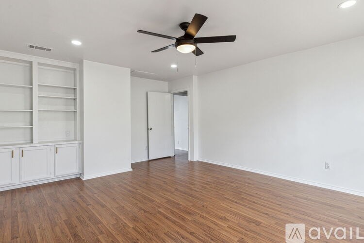 A room with a ceiling fan and wooden flooring.