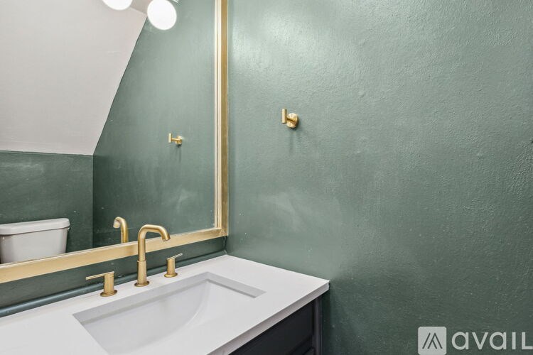 A bathroom with a white sink and a gold-framed mirror.