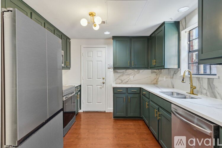 A kitchen with a refrigerator, cabinets, and a sink.