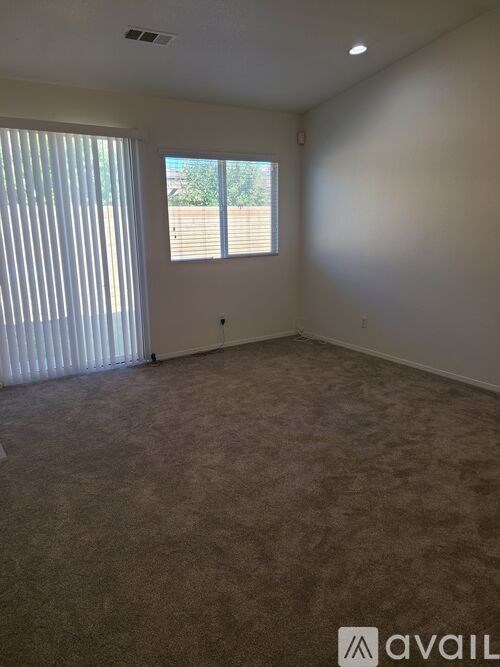 A room with a carpeted floor and a window with blinds.
