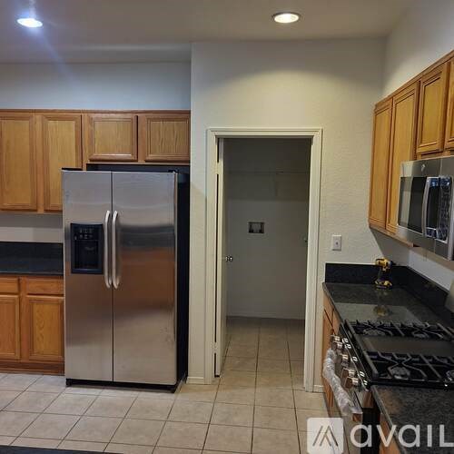 A kitchen with a stainless steel refrigerator and wooden cabinets.