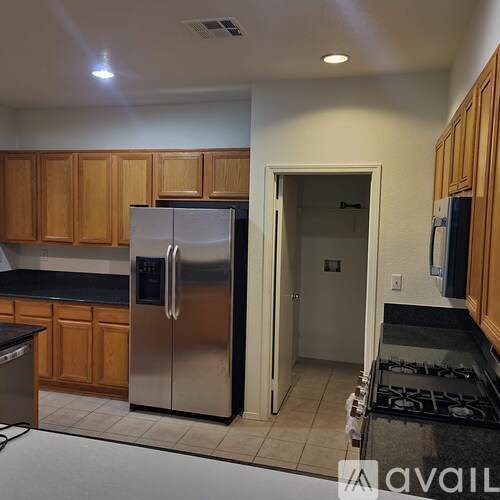 A kitchen with a stainless steel refrigerator and wooden cabinets.
