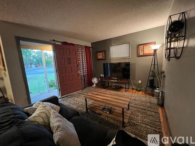 A living room with a couch, a television, and a red door.