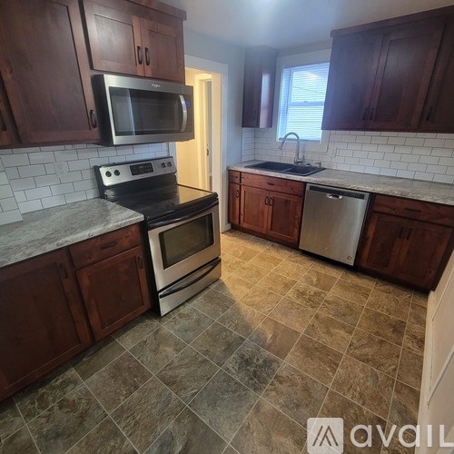 A kitchen with brown cabinets and a tiled floor.