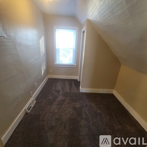 A room with a window and carpeted floor.