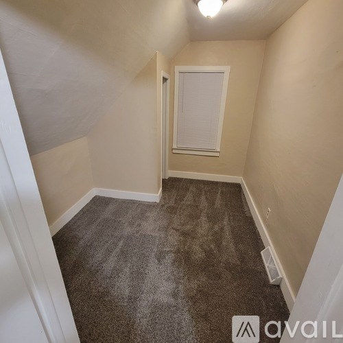 A carpeted room with a door and a window.