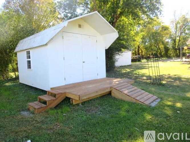 A small white shed with a wooden deck in front.