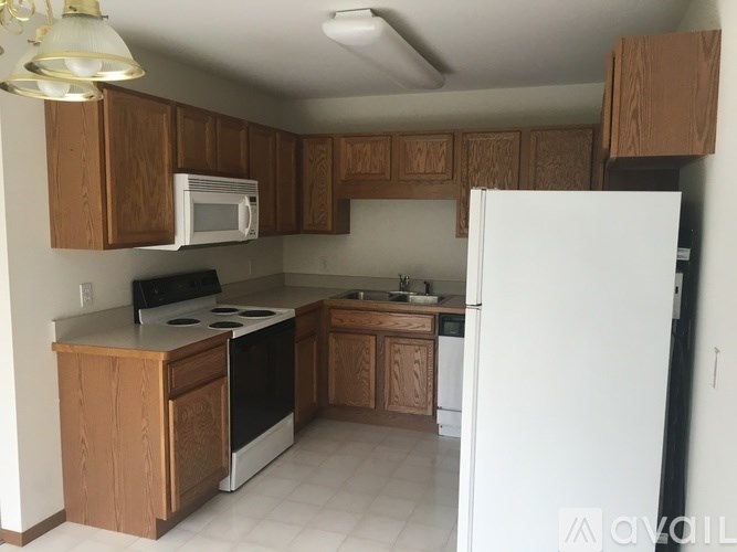 A kitchen with brown cabinets and white appliances.