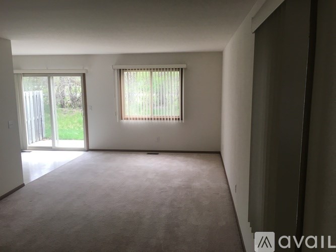 A room with a carpeted floor and a window with blinds.