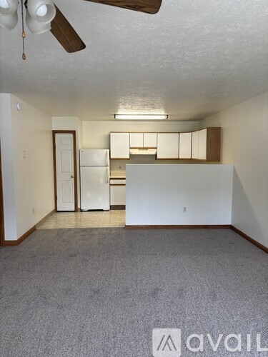 A room with a ceiling fan and a refrigerator.