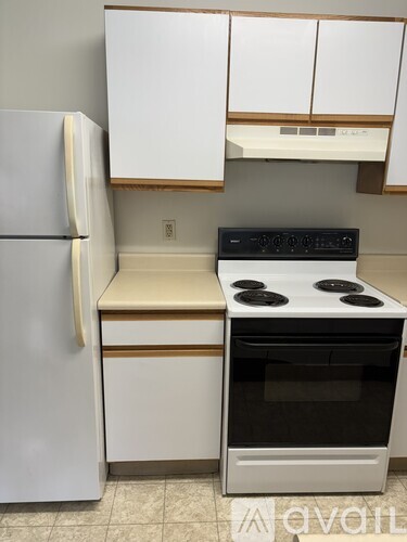 A white refrigerator stands next to a white stove in a kitchen.
