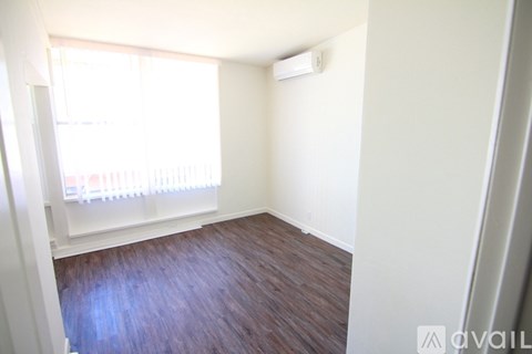 A room with a window and wooden flooring.