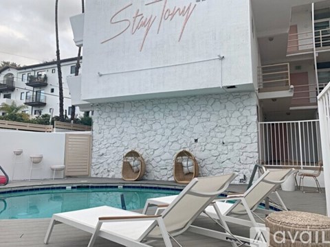 A pool area with lounge chairs and a stone wall with the words "Stay Tuned" written on it.