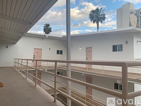 A balcony with a metal railing and a palm tree in the background.