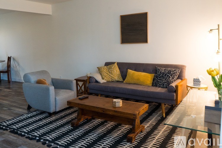A living room with a grey couch, a wooden coffee table, and a grey armchair.
