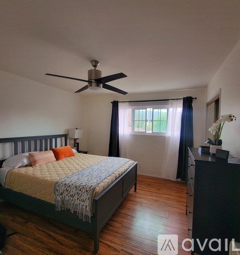 A bedroom with a bed, dresser, and ceiling fan.