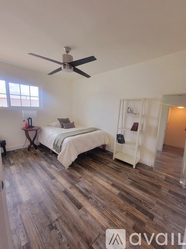 A bedroom with a bed, a nightstand, and a ceiling fan.