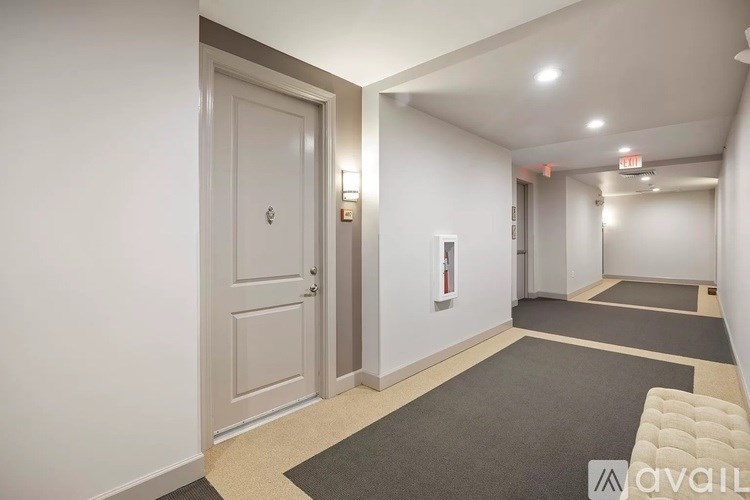 A hallway with a carpeted floor and a door on the left.
