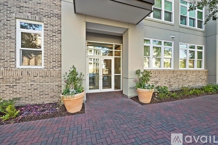 A building entrance with a brick pathway and potted plants on either side.