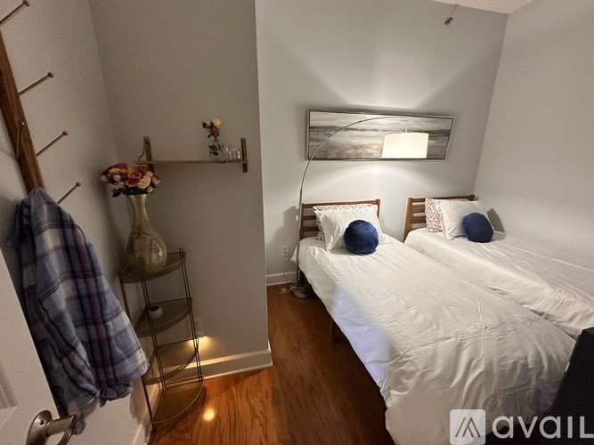 A bedroom with a bed, a nightstand, a chair, a shelf, a painting, a lamp, a vase, and a coat rack.