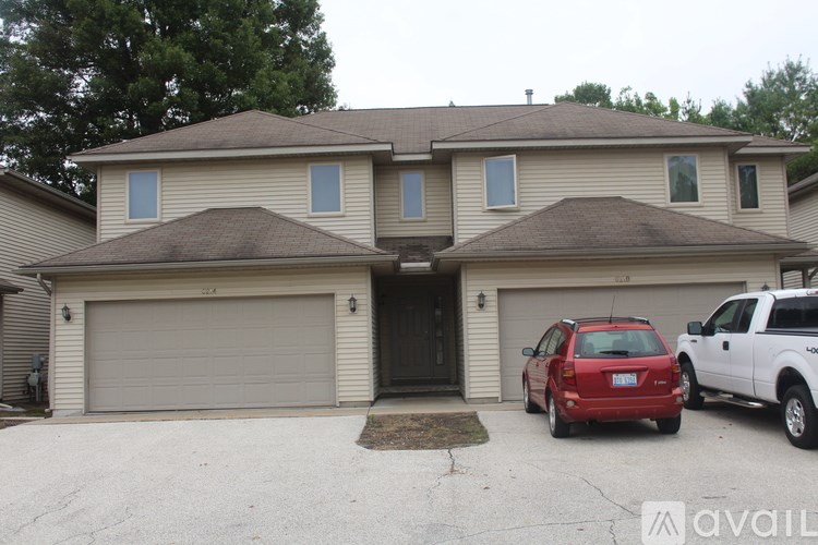 A two-story house with a red car and a white truck parked in front.