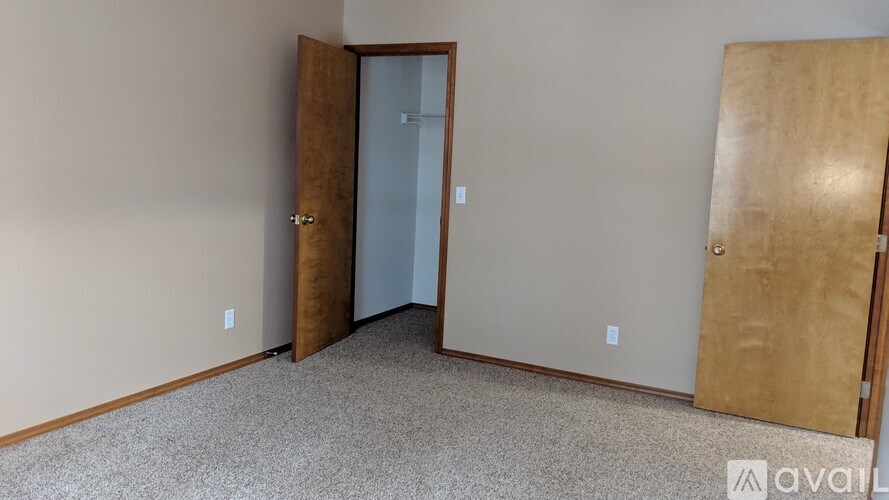 A room with a carpeted floor and two wooden doors.