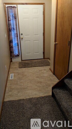 A hallway with a carpeted floor, a white door, and a wooden door.